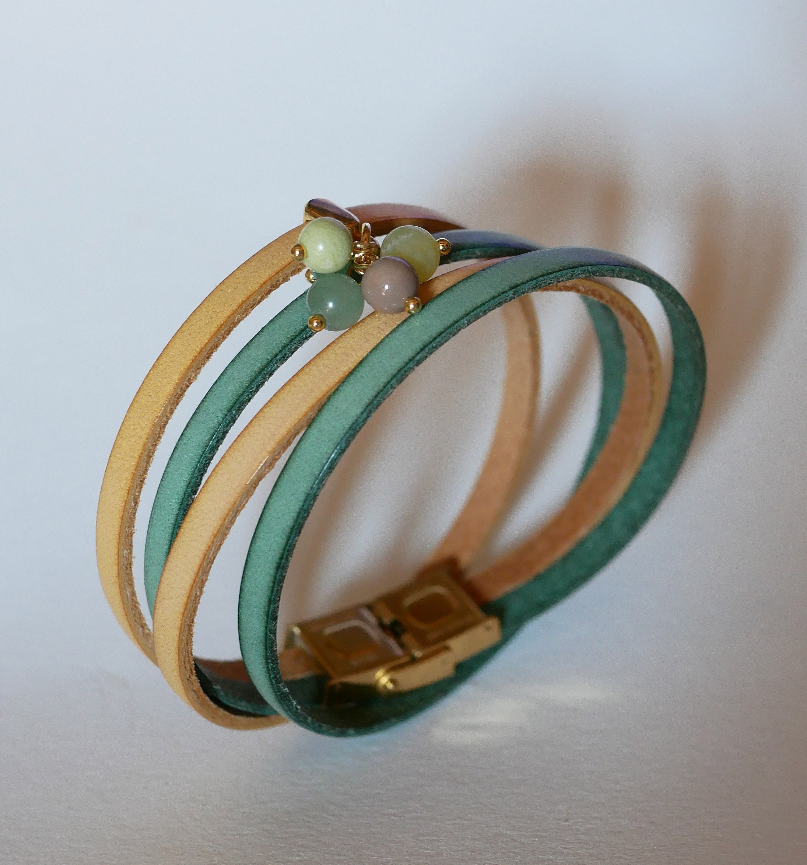 Dobbelt skinnarmb&aring;nd dekorert med myke, gr&oslash;nne perler og gullspenne