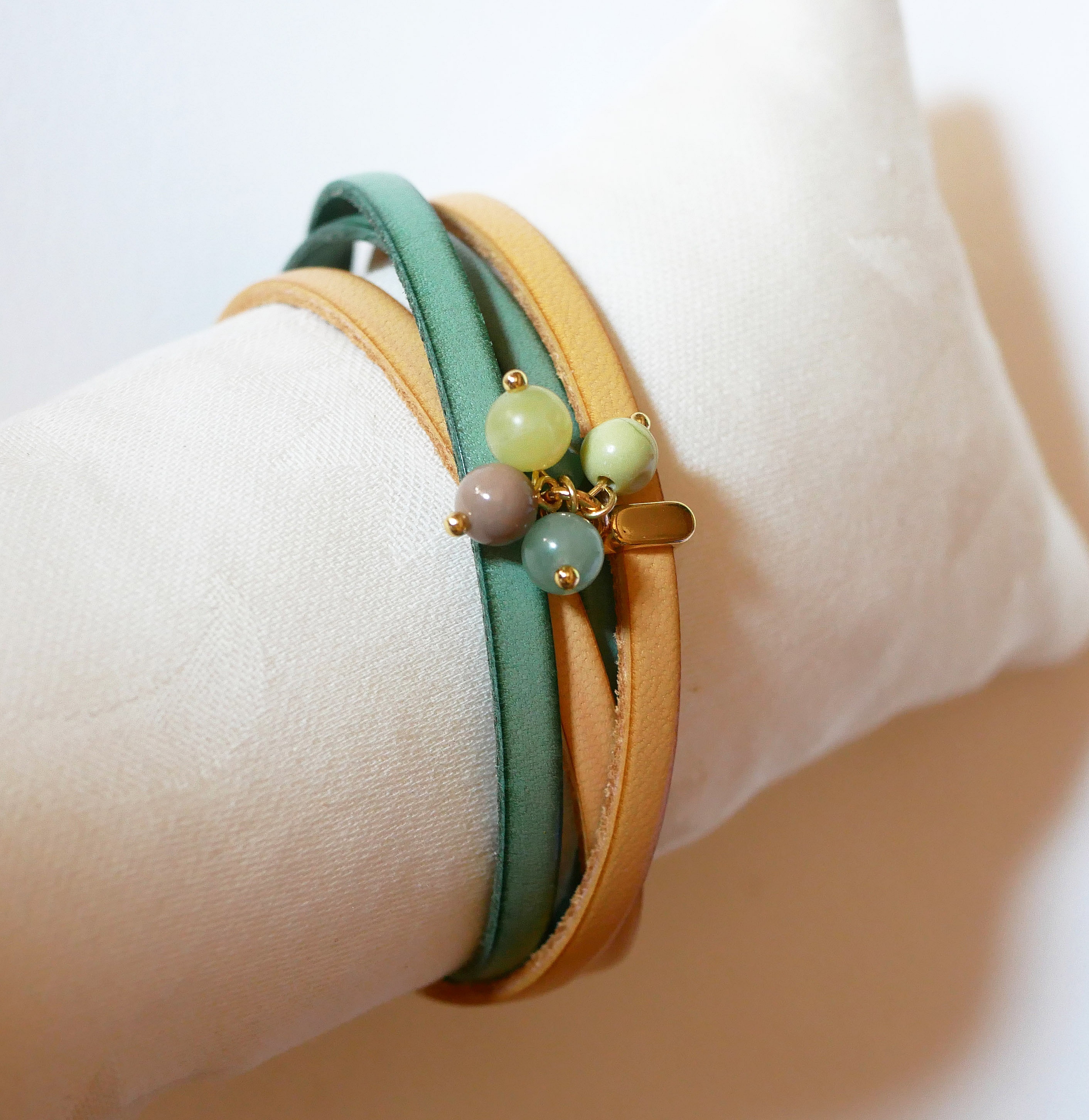 Dobbelt skinnarmb&aring;nd dekorert med myke, gr&oslash;nne perler og gullspenne