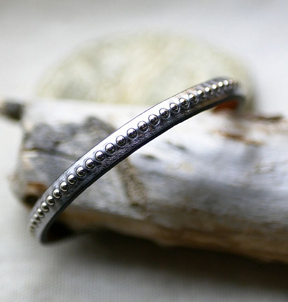 Damearmb&aring;nd i m&oslash;rkegr&aring;tt metallisk skinn med s&oslash;lvperler 