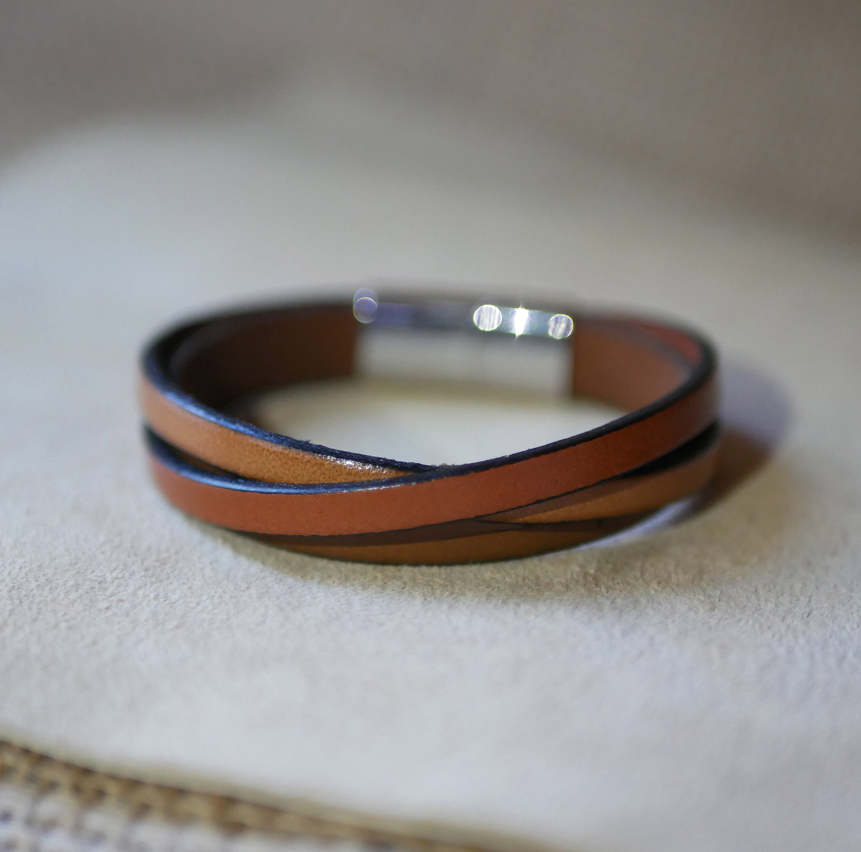 Tofarget mansjettarmb&aring;nd i krysset skinn med inngravert budskap for menn