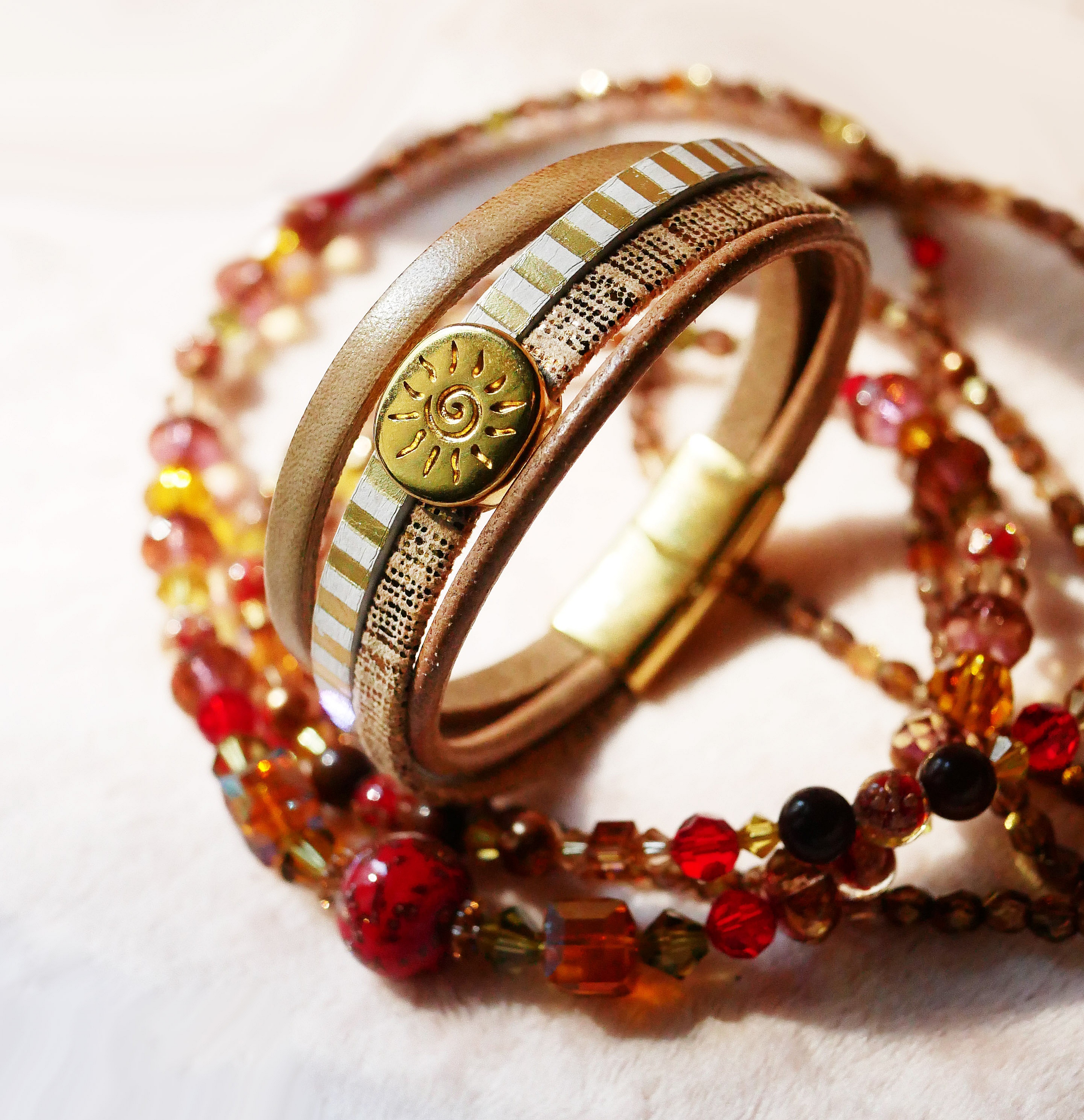 Mansjettarmb&aring;nd i skinn med flere lenker og solstr&aring;le-l&oslash;kke i gull