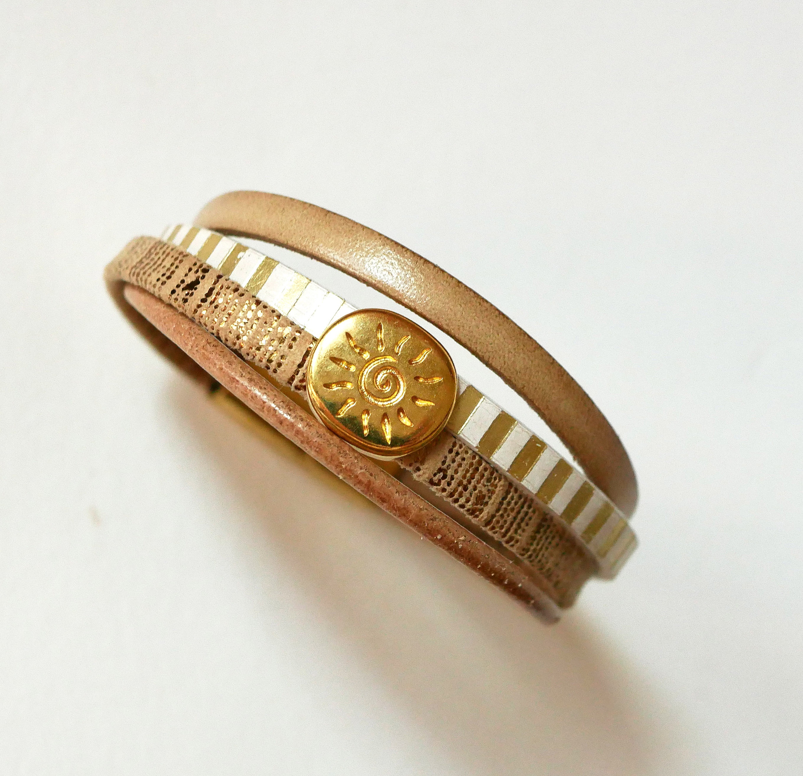 Mansjettarmb&aring;nd i skinn med flere lenker og solstr&aring;le-l&oslash;kke i gull