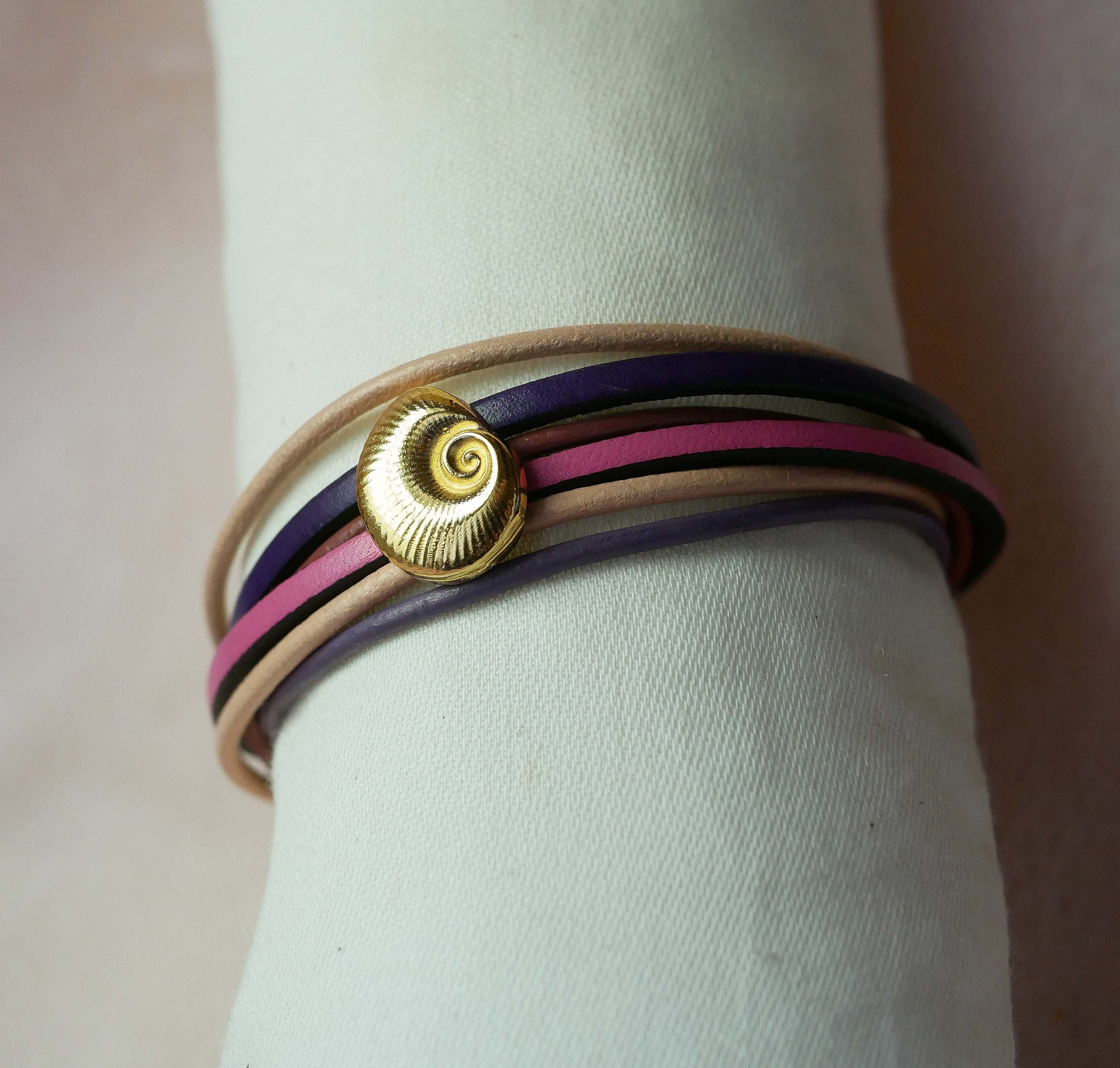 Flerleddsarmb&aring;nd i ferskenfarget og lilla skinn med skjelldekorasjon i gull