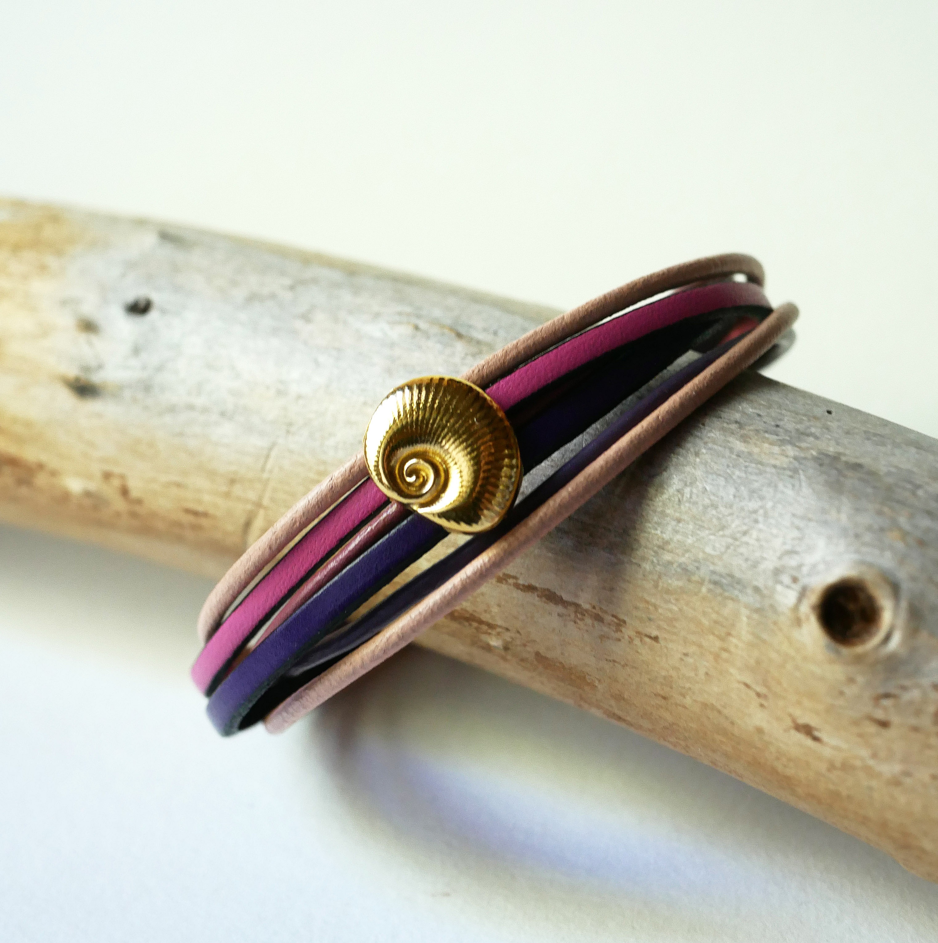 Flerleddsarmb&aring;nd i ferskenfarget og lilla skinn med skjelldekorasjon i gull