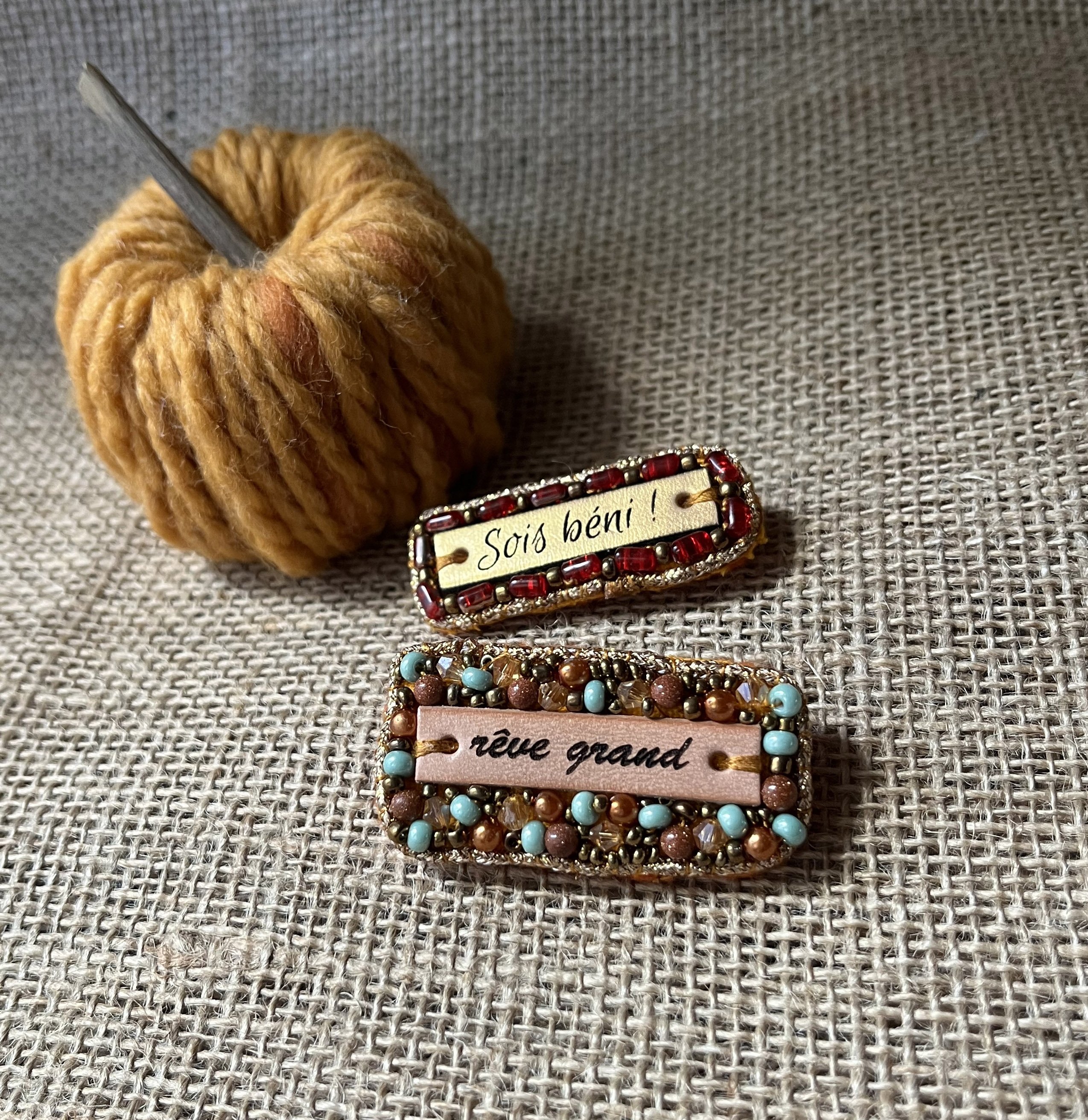 Broche à message en cuir gravé "sois béni" en perles rouges et dorées 